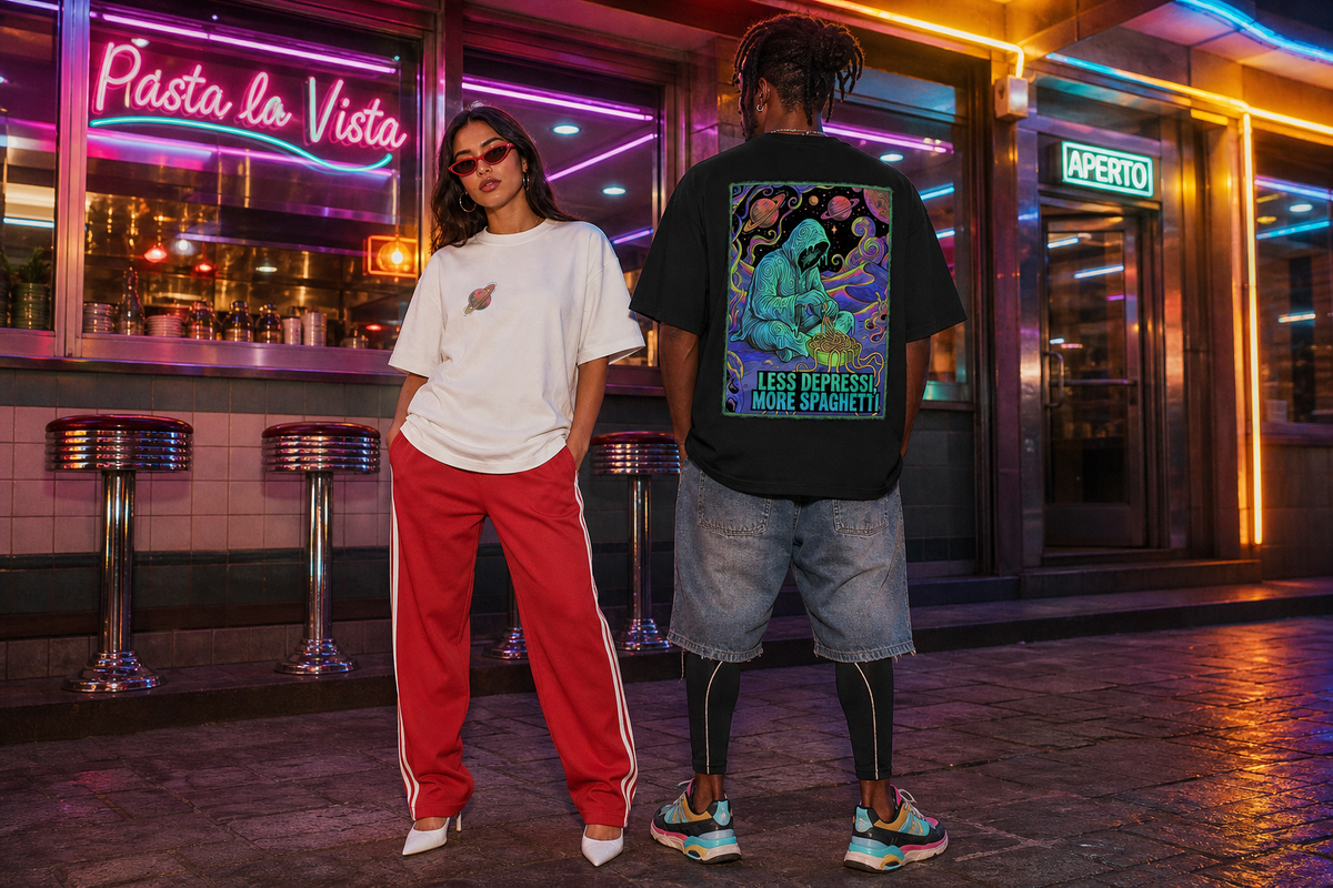 Two models standing on a city street in front of a neon-lit bar, one wearing a white t-shirt and red track pants, and the other wearing a black graphic t-shirt with a large colorful back print and denim shorts.